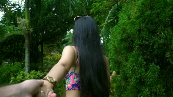 亚洲女孩在热带花园散步和牵着男朋友的手