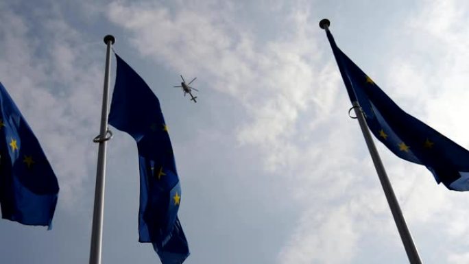 在春天的慢镜头中，三个欧盟标准令人印象深刻地飘扬着，背景是一架警用直升机。