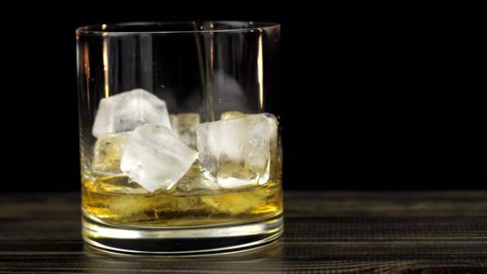 威士忌被倒入加冰的玻璃杯中