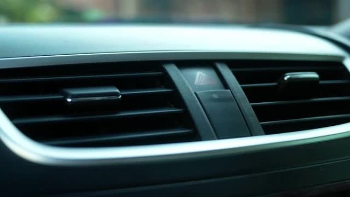 驾驶员手的特写是按下汽车仪表板上的紧急按钮。技术和运输概念。