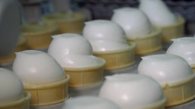 冰淇淋自动生产线。用冰淇淋填充威化饼杯。蛋筒冰淇淋。冰淇淋厂