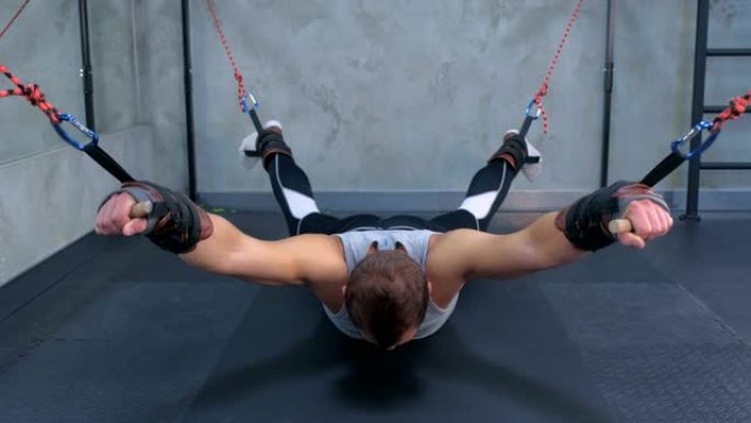 运动员使用教练在健身房进行肌筋膜伸展，在垫子上向下身体。