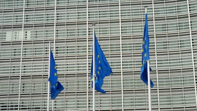 在一个阳光明媚的春天，三面带有黄色星圈的欧盟旗帜在布鲁塞尔的欧盟办公室飘扬。