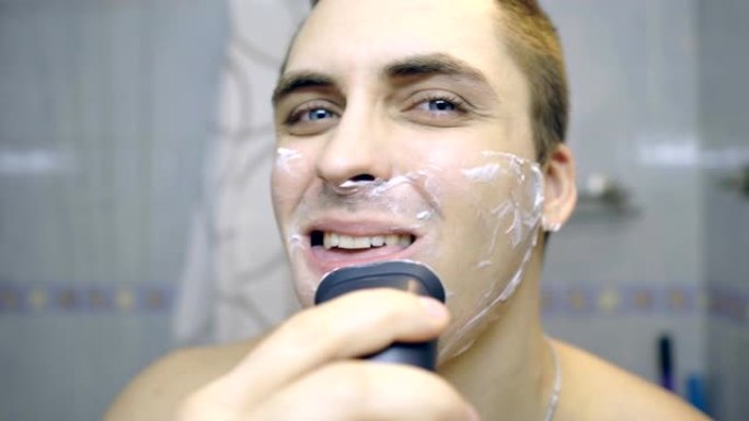 那家伙在浴室里用电动剃须刀刮胡子。那家伙在照镜子。