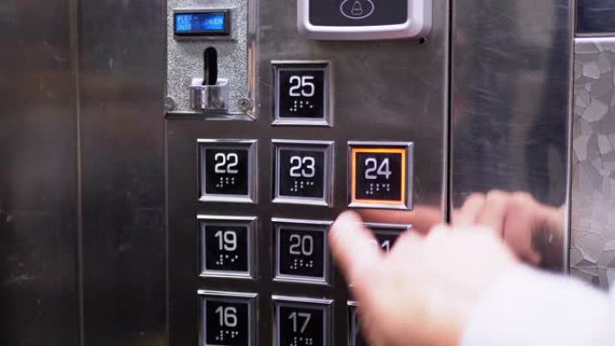 女性手按下面板上24层的按钮进入电梯轿厢