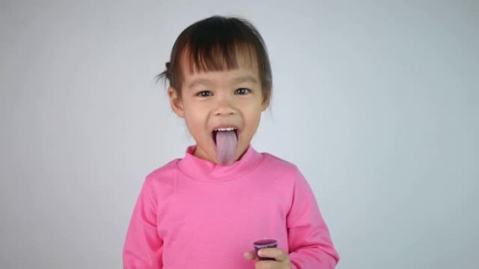 一个快乐微笑的亚洲儿童女孩的肖像，喜欢吃白色背景上孤立的明胶甜点。