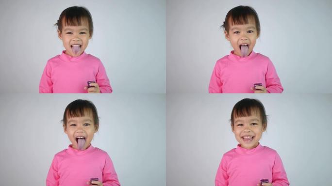 一个快乐微笑的亚洲儿童女孩的肖像，喜欢吃白色背景上孤立的明胶甜点。