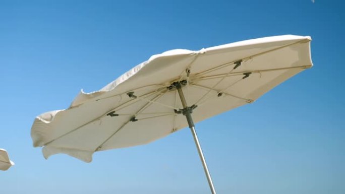 科斯塔德尔马雷斯梅海岸。太阳伞在强风中挥舞的特写镜头。西班牙。慢动作。高清