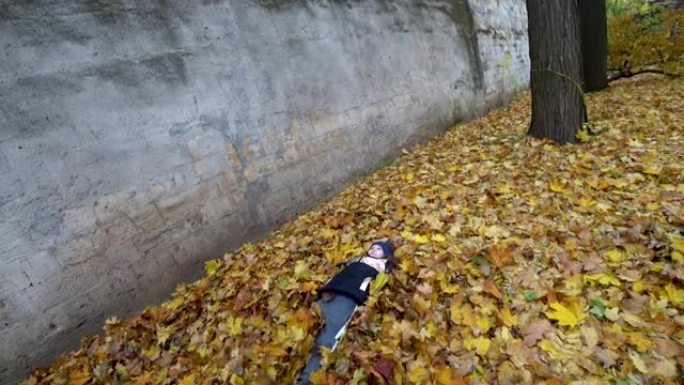 小女孩正在秋天的公园里玩树叶。