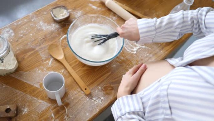 孕妇在厨房里做早餐时，在碗里搅拌牛奶的特写镜头。