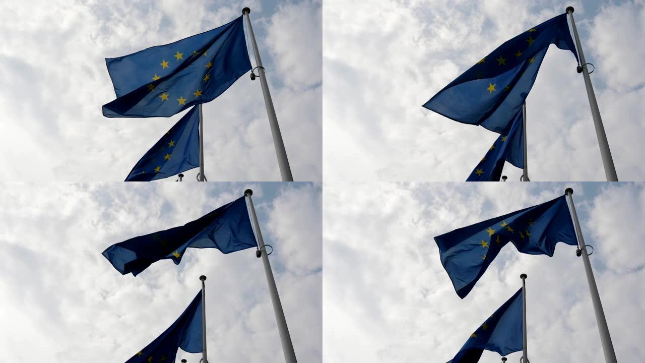 在春天的一个阳光明媚的日子里，两面欧盟旗帜在布鲁塞尔庄严地飘扬。天空是蓝色和白色的