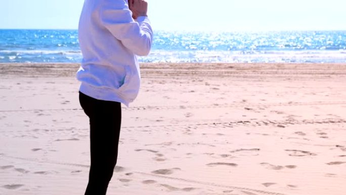 女孩在沙滩上做蹲坐健身户外运动训练。