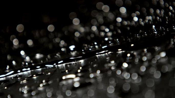 黑色和灰色水的奇妙宏观镜头溅落在崎surface的表面上，以缓慢的动作闪烁而喜气洋洋的雨滴。