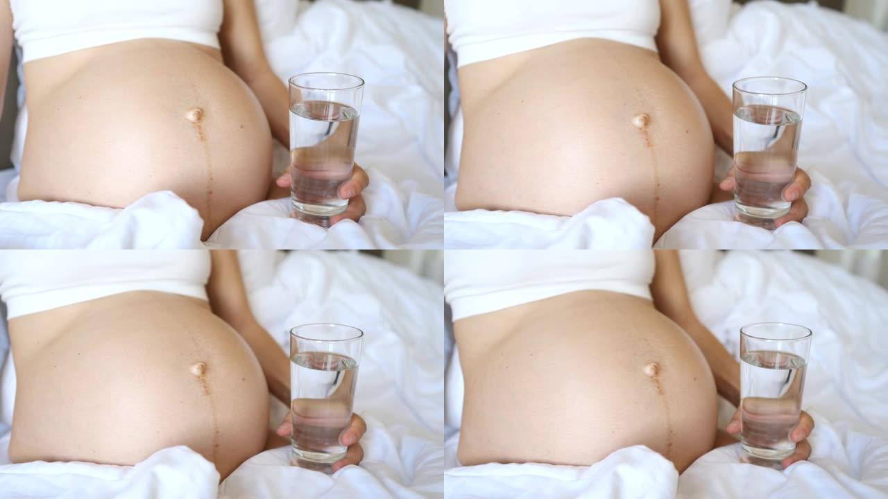 孕妇肚子和一杯水的特写