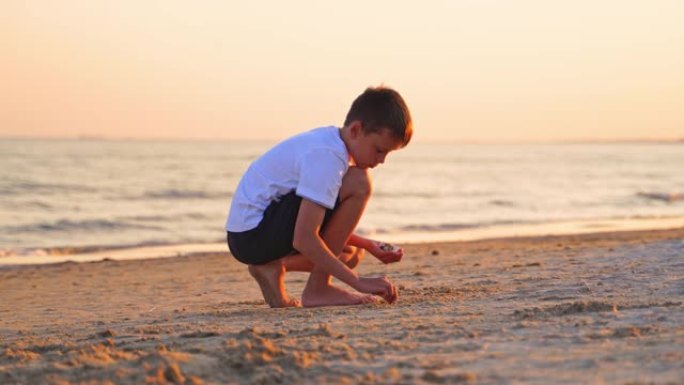 安静的男孩在海水背景下的沙滩上玩耍。