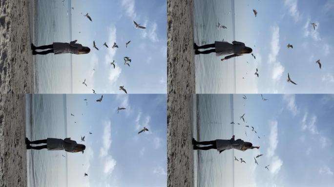 年轻女孩在海滩上喂海鸥。垂直慢动作视频