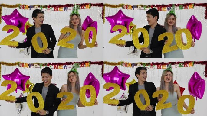 亚洲情侣情人拿着2020数字在酒吧庆祝新年，在新年派对上大喊大叫，笑着倒计时到午夜