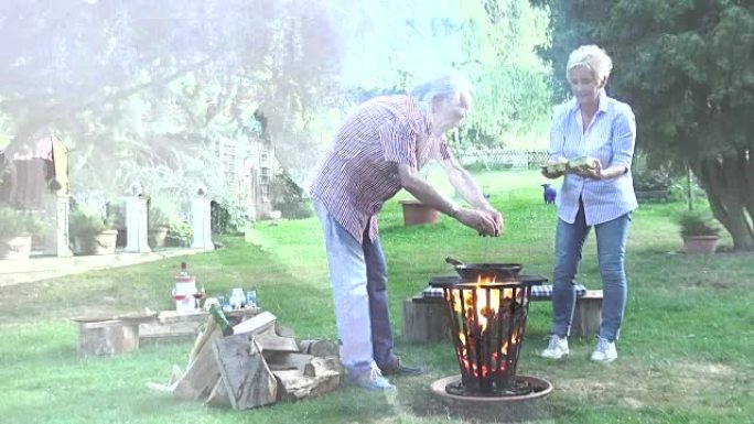 充满魅力的男人在篝火上的锅里准备煎鸡蛋，他的年轻妻子帮助他