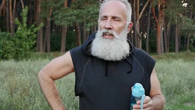 大胡子老人跑步后喝水。慢动作