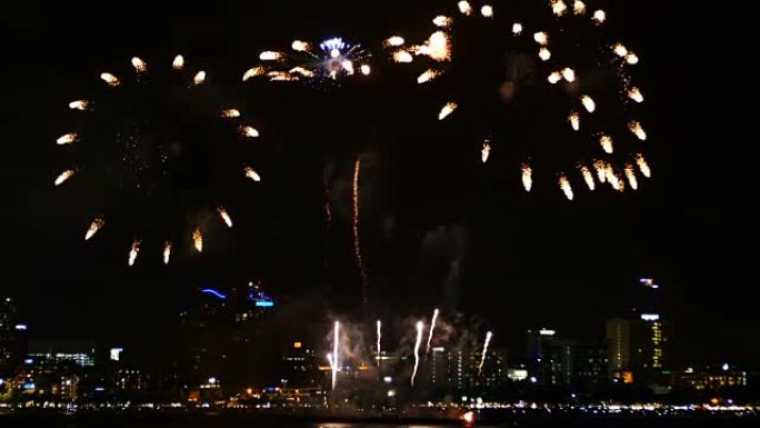 天空中真正的烟花节的4k镜头，用于夜间庆祝，背景为城市景观。五颜六色的烟花庆祝夜晚