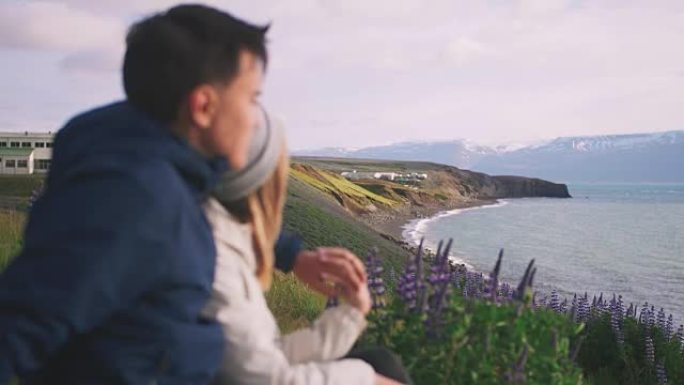 年轻夫妇拥抱并欣赏冰岛沿海山脉的壮丽景色