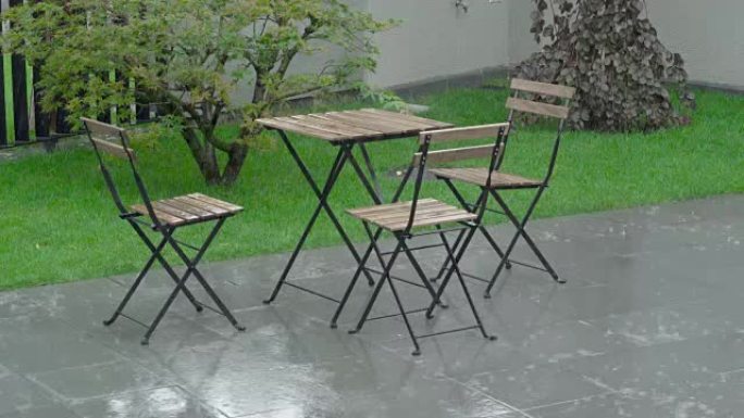 大雨在后院和潮湿的家具上猛烈袭击。桌子和炭被浸湿了。