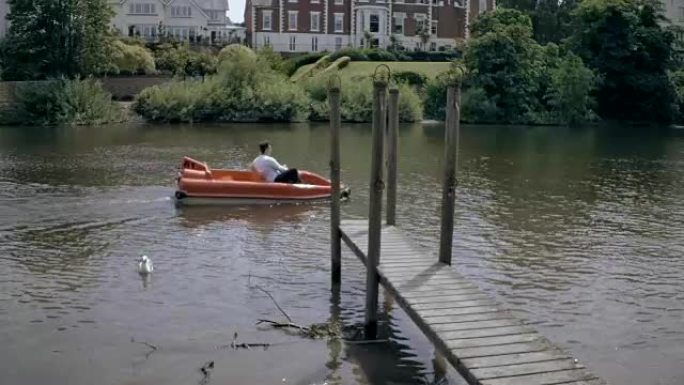 夫妇在河边码头旁边的踏板船上接吻。浪漫的夏日城市场景。