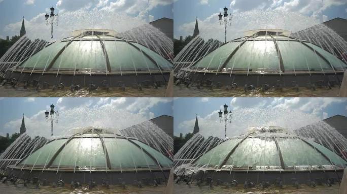 夏天美丽的城市喷泉。水飞溅成一圈。