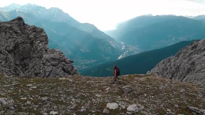 航拍:一对背包客在背光慢镜头中徒步前往山顶