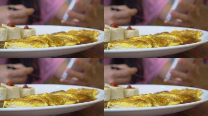 亚洲妇女在酒店吃早餐。包括三文鱼煎蛋卷、汉堡、肉松、烤面包、番茄酱。
