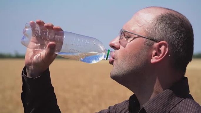 农民的特写镜头正在用ecoonamine从清澈的瓶子里喝冷水