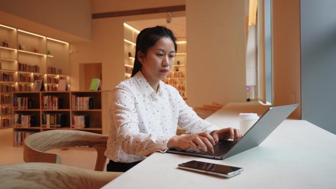 女性在图书馆笔记本电脑上工作