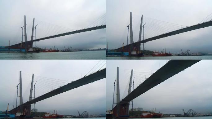 符拉迪沃斯托克 (Vladivostok) 港口的商船站在巨大桥梁的柱子周围