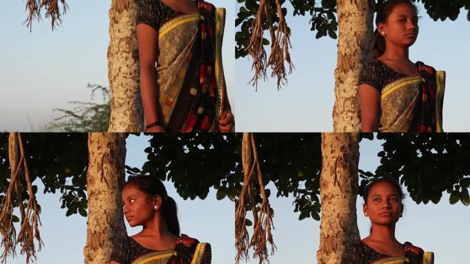 渴望爱情的夏日里，印度少年美丽的女孩在树下的山顶上等着看快乐快乐的太阳热带炎热明亮的阳光内容看着相机