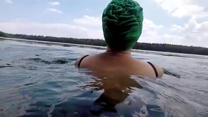 戴着泳帽在湖里游泳的女人