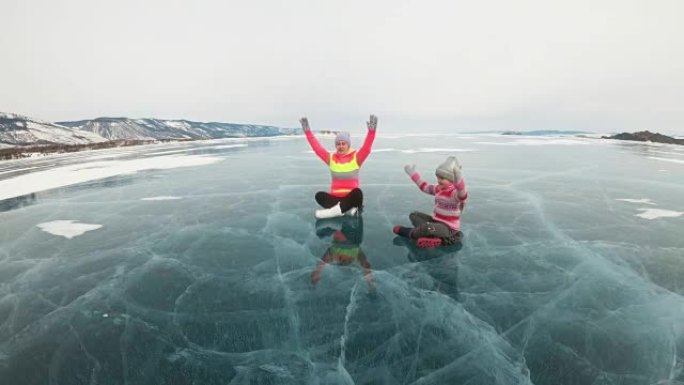 一家人在冬天练瑜伽。女人在大自然的冰上做伸展和冥想。母亲和女儿在裂缝里的冰上练习瑜伽。女孩们在户外做