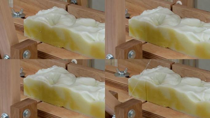 肥皂切割机的特写。一根绳子从一块手工制作的肥皂上切出一块矩形。