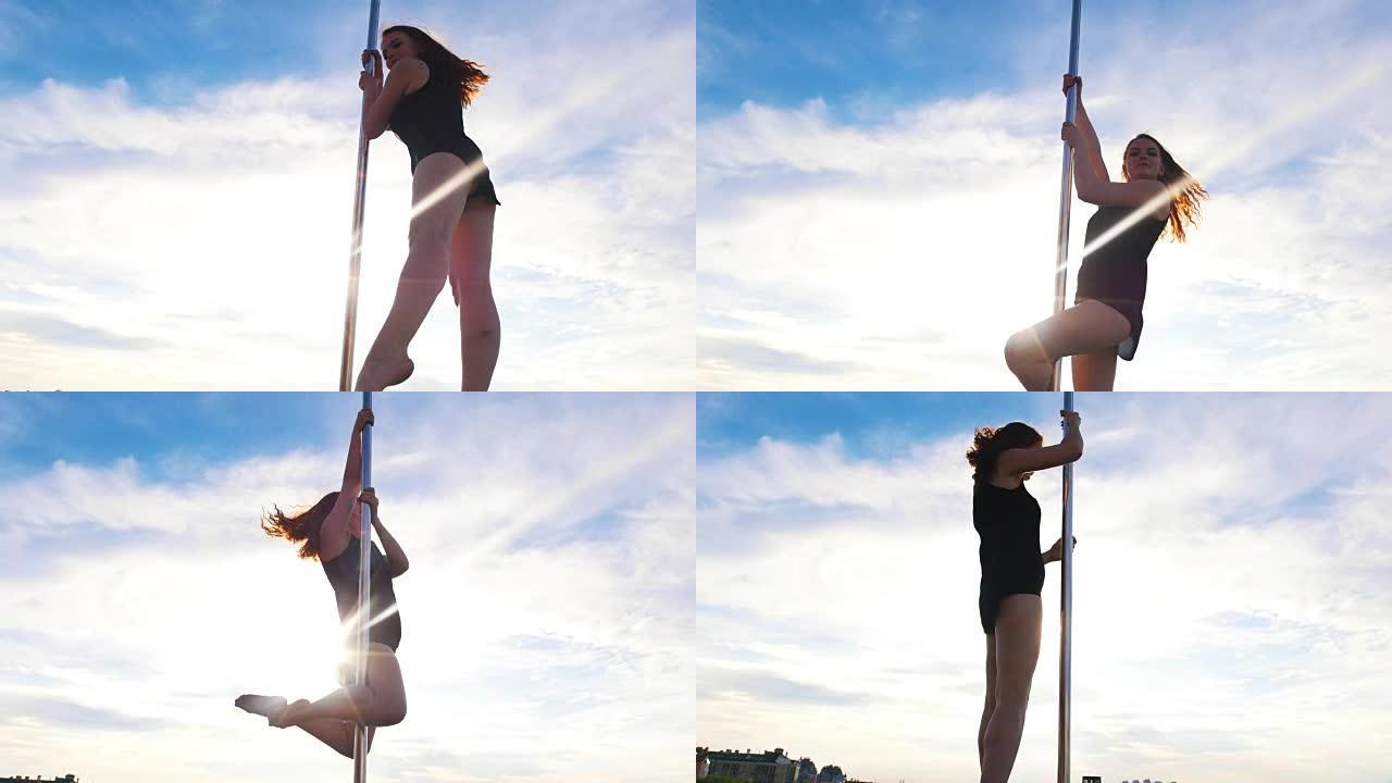 年轻女子钢管舞演员在杆子上对着天空表演