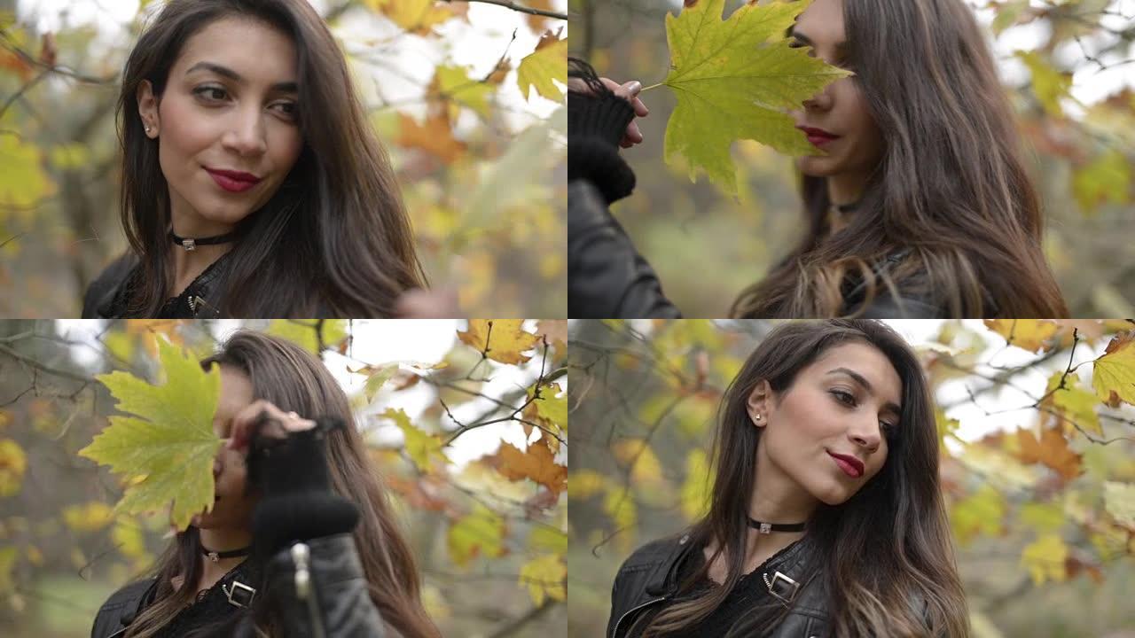 一名中东妇女在秋季和大自然中与干燥的叶子合影。