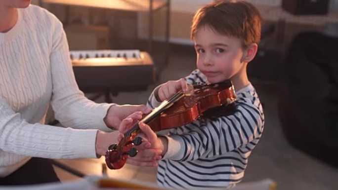 年轻女子教小男孩如何拉小提琴