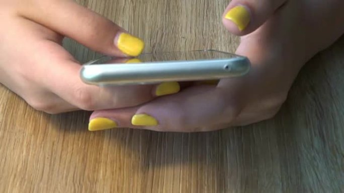 带有智能手机的黄色修指甲的女性手