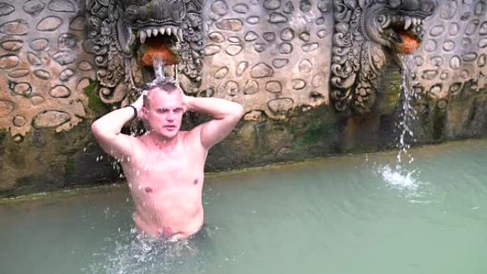 一名穿着泳衣的男子站在一个装有硫化氢水的水池中的水流下