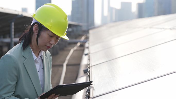 女性工程师拿着平板在光伏太阳能发电站工作