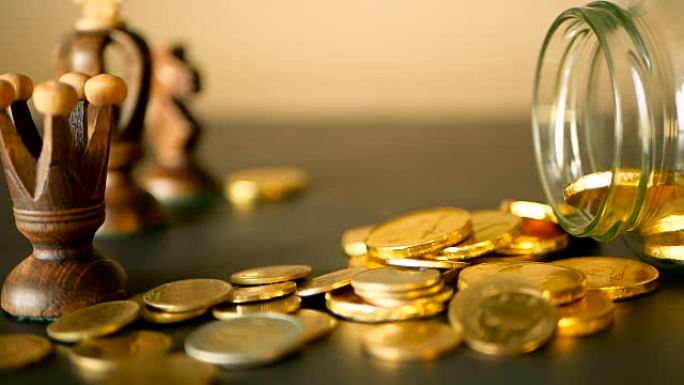 黑桌上有金币、象棋和旋转便士的特写静货。黄色硬币从罐子里掉了出来。