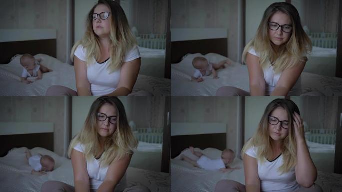 精神卫生，担心的不高兴的女人坐在家里爬行婴儿的背景下，坐在床上