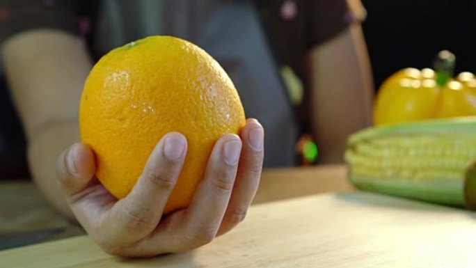 亚洲女性在厨房的手掌上露出干净的鲜橙色水果。准备食物