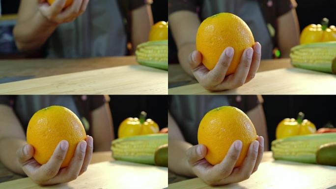 亚洲女性在厨房的手掌上露出干净的鲜橙色水果。准备食物