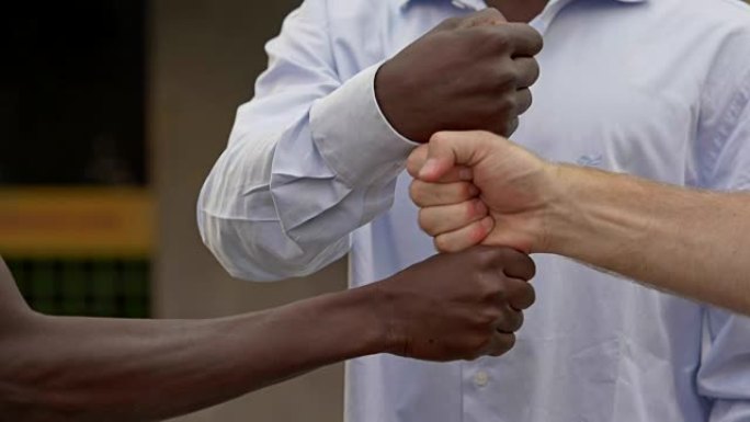 各国人民之间的团结。黑人和白人触摸的闭合拳头-慢动作