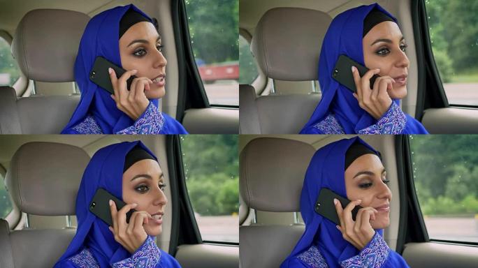 戴着头巾的年轻穆斯林妇女坐在乘客后座上的汽车上，在手机上聊天，微笑着