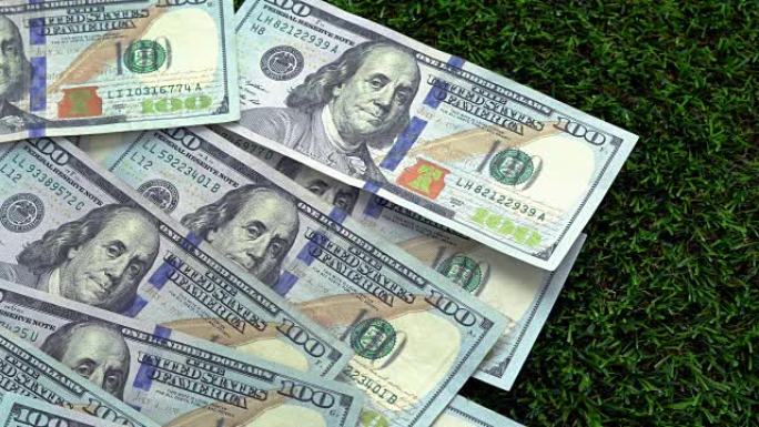 足球商业，足球赌博的概念:一个足球掉在美钞上，它散布在绿色的草地上。